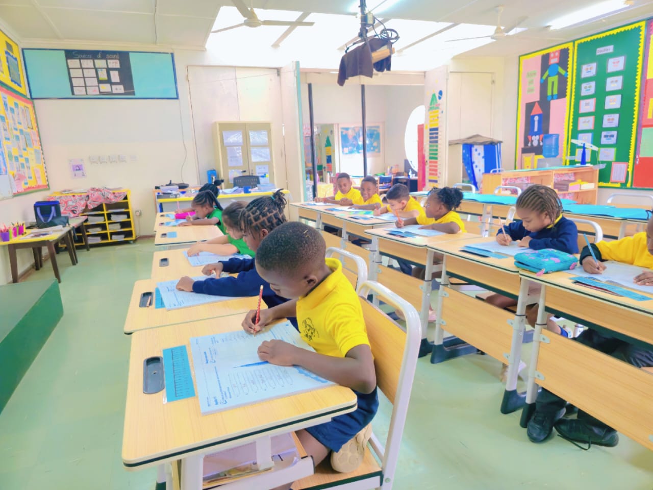 Concentration in a full primary classroom — every desk taken, every pupil writing.