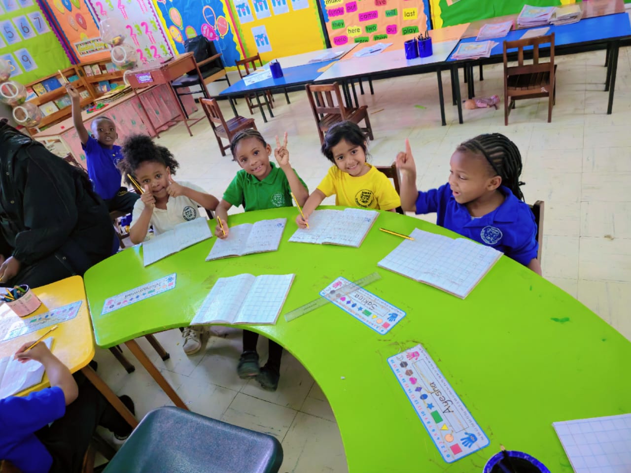 Hands up at the group table: a lively question-and-answer moment in Lower Primary.