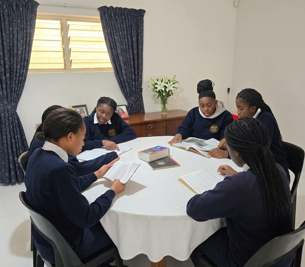 Boarders reading together around a table in the house common room